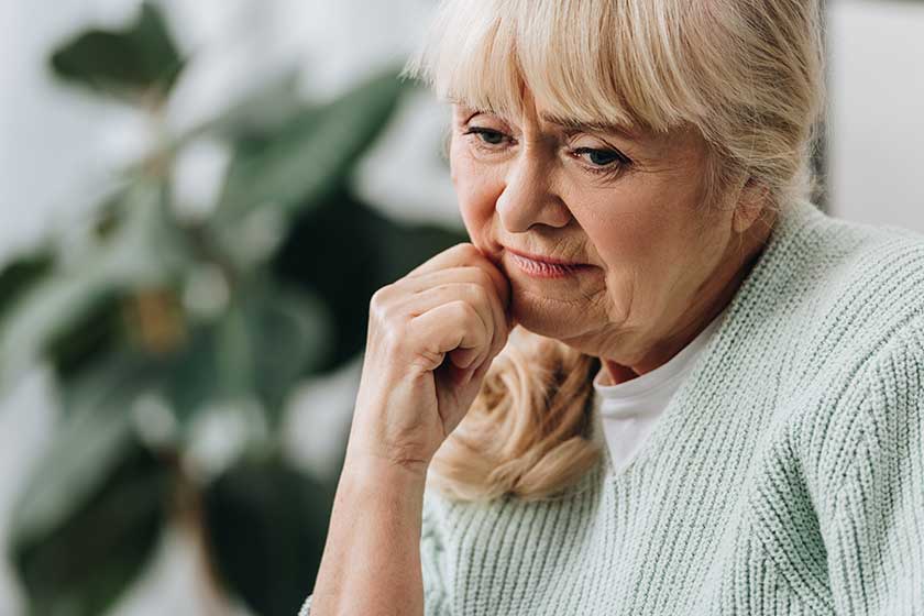 Pensive blonde senior woman in living room