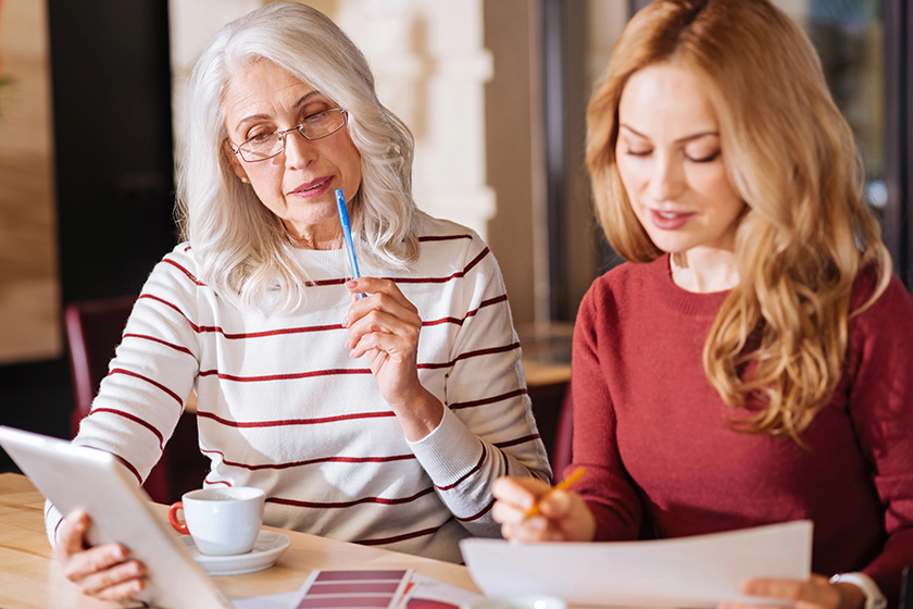 Thoughtful senior woman looking at the tablet while thinking 